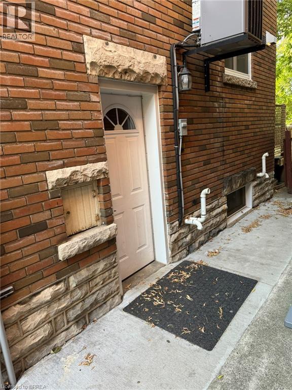 A brick building with a white door and a black mat on the sidewalk.