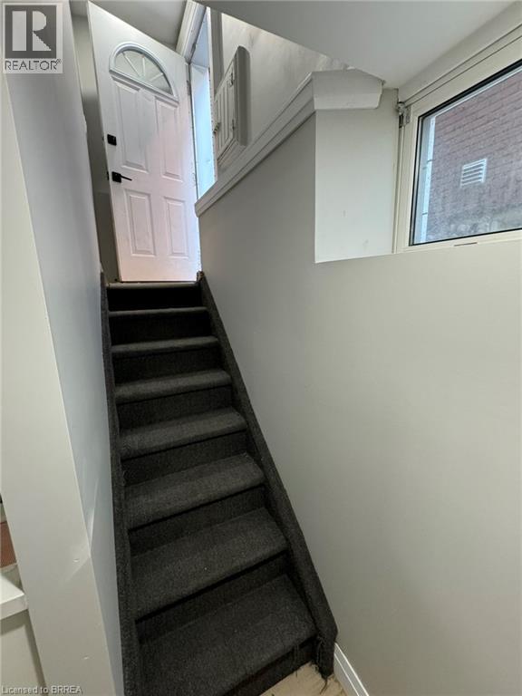 A staircase with a black carpeted runner and white walls.