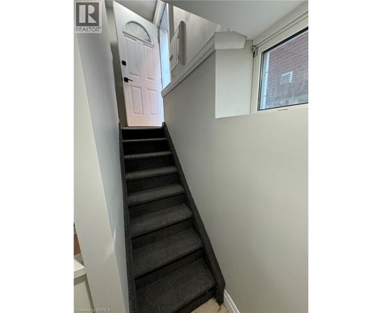 A staircase with a black carpeted runner and white walls.