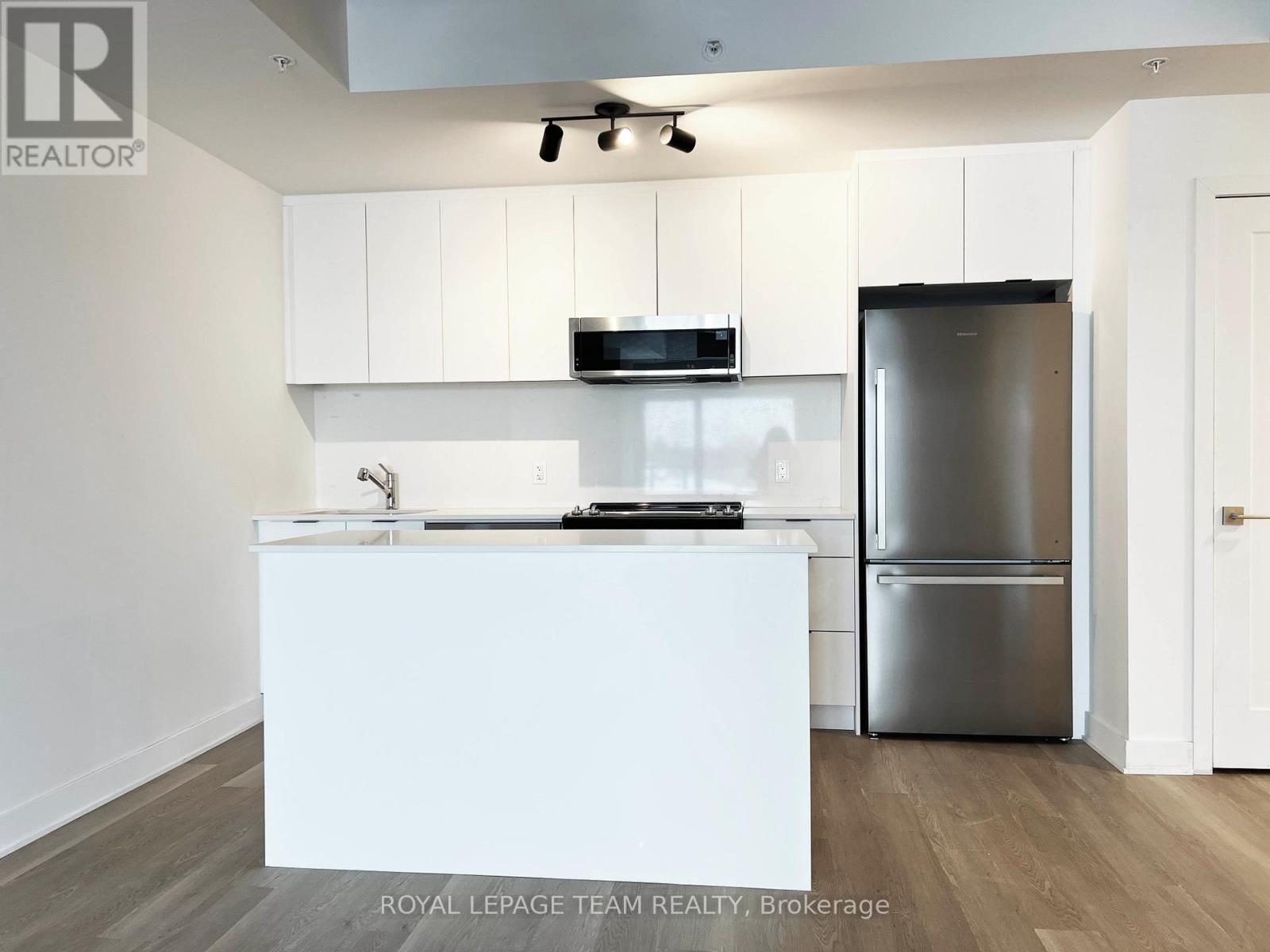 A modern kitchen with white cabinets and a stainless steel refrigerator.