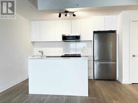 A modern kitchen with white cabinets and a stainless steel refrigerator.