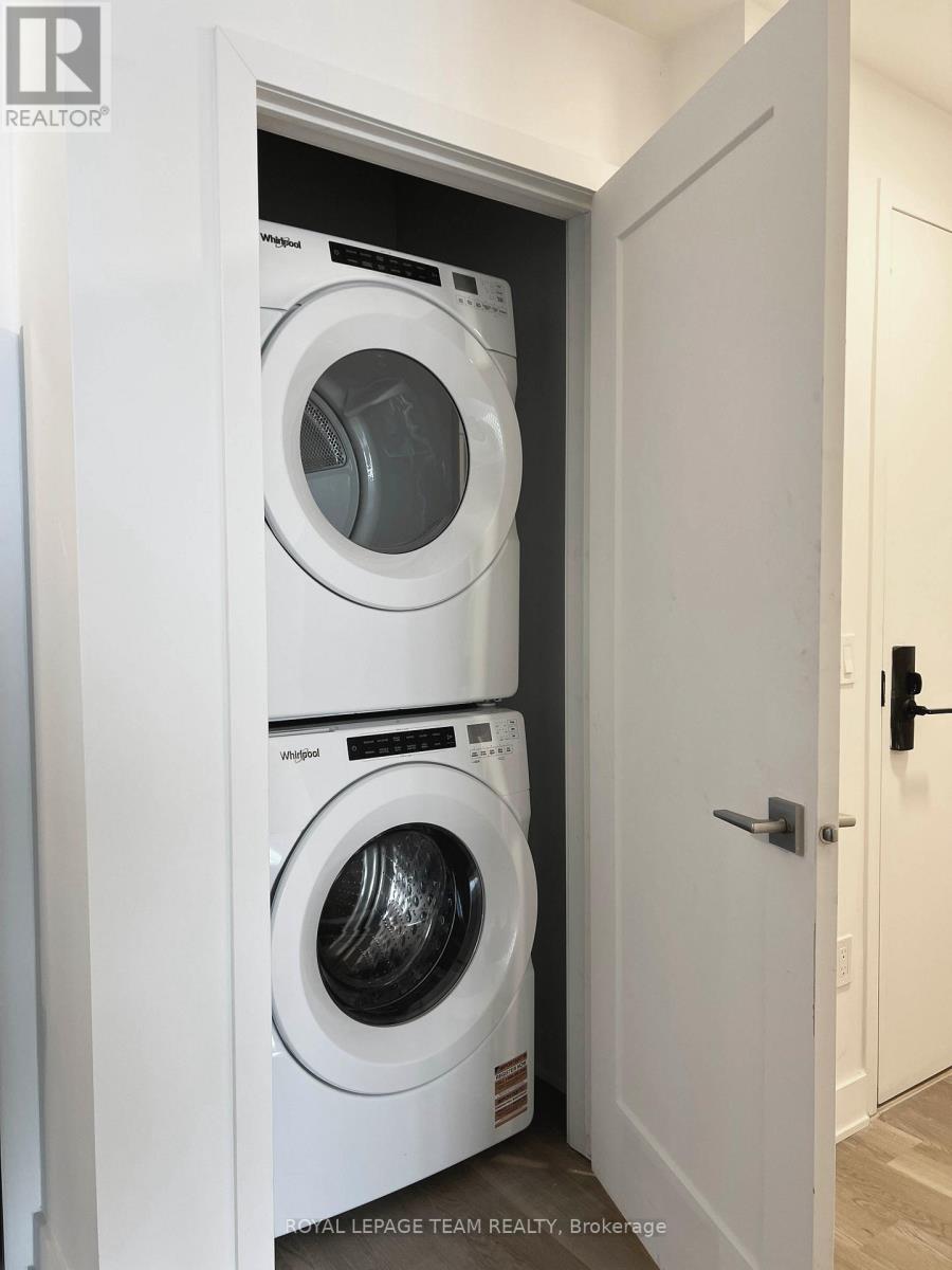 A white washing machine is in a small space between a door and a wall.