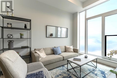 A living room with a couch, chair, and a table with a vase of flowers on it.