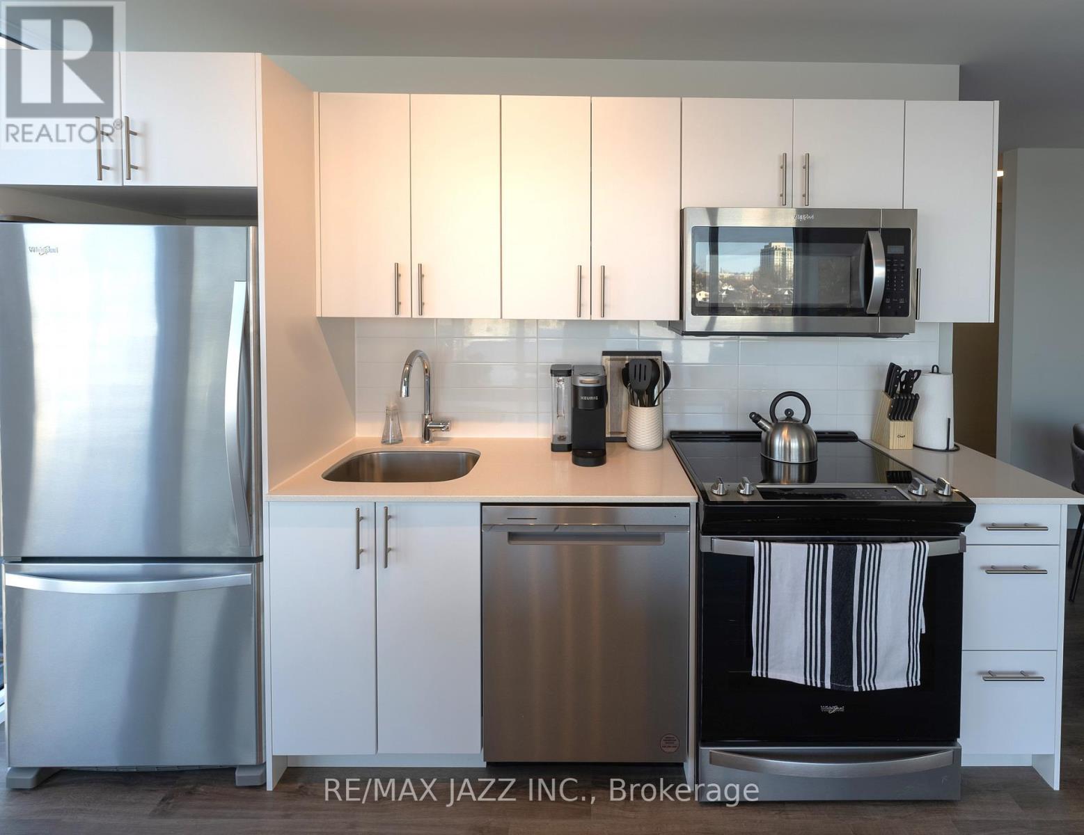 A kitchen with white cabinets and a stainless steel refrigerator.