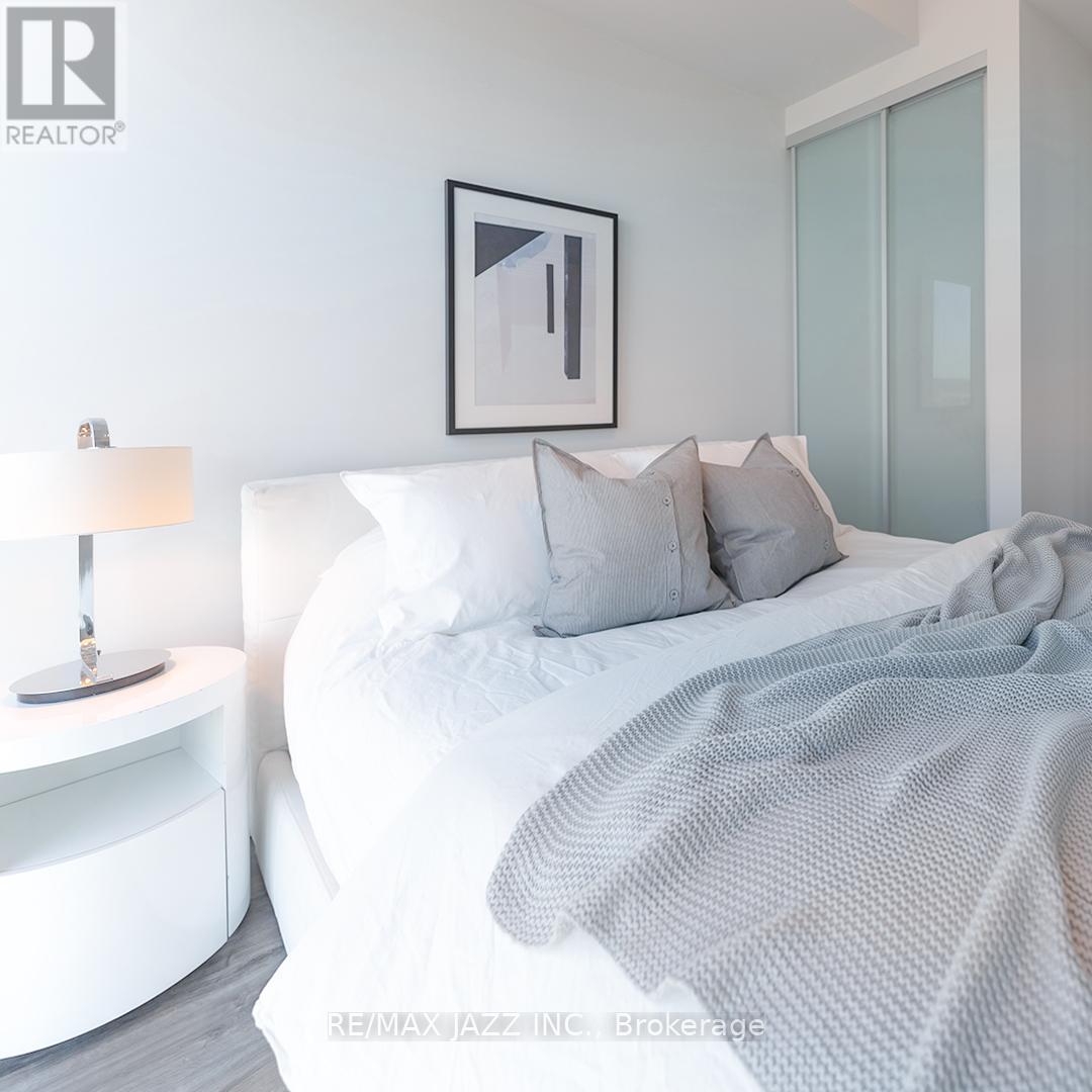 A bedroom with a white bed and a grey blanket.