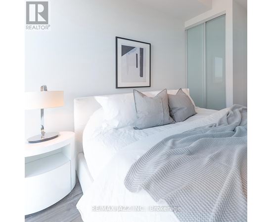 A bedroom with a white bed and a grey blanket.