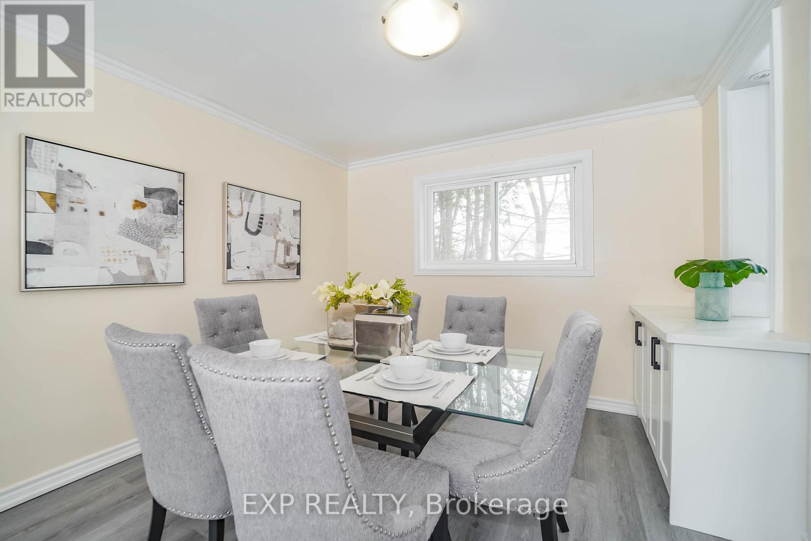 A dining room with a glass table and grey chairs.