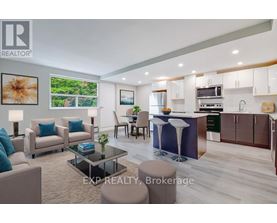 A modern living room with a kitchen area in the background.