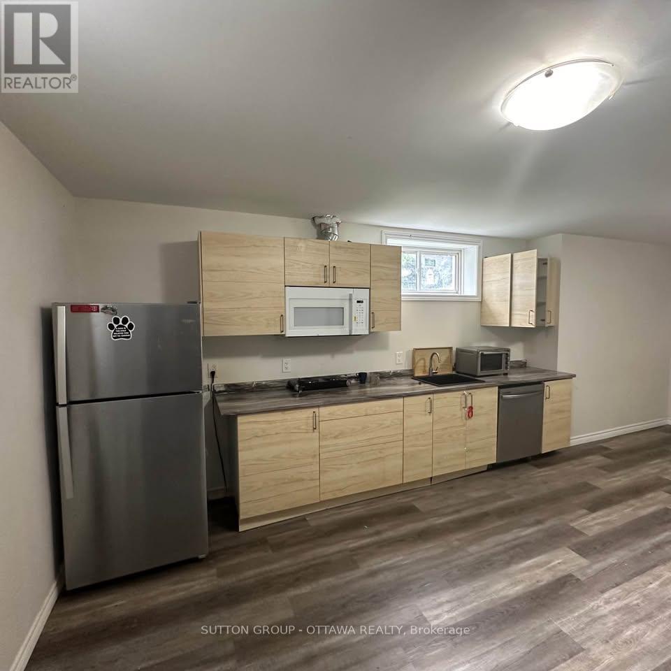 A kitchen with a refrigerator, microwave, oven, and cabinets.