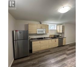 A kitchen with a refrigerator, microwave, oven, and cabinets.