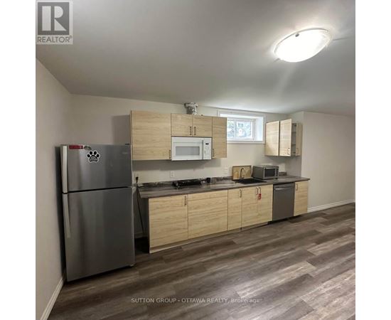 A kitchen with a refrigerator, microwave, oven, and cabinets.