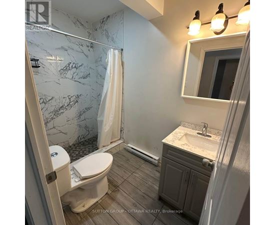 A bathroom with a marble shower and a white toilet.