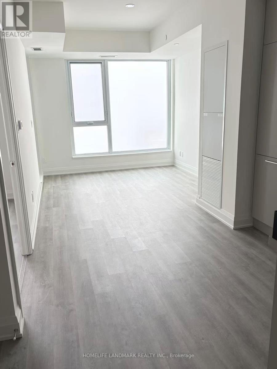 A spacious room with a large window and wooden flooring.