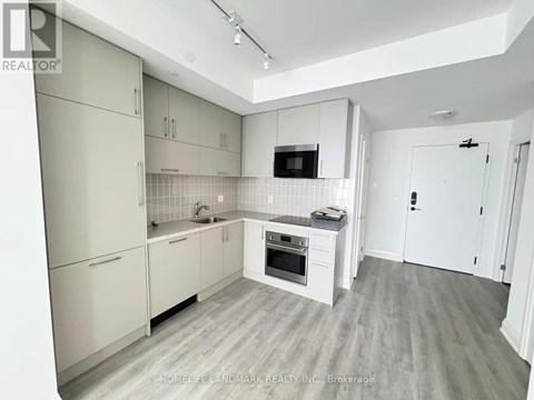 A kitchen with white cabinets and a wooden floor.
