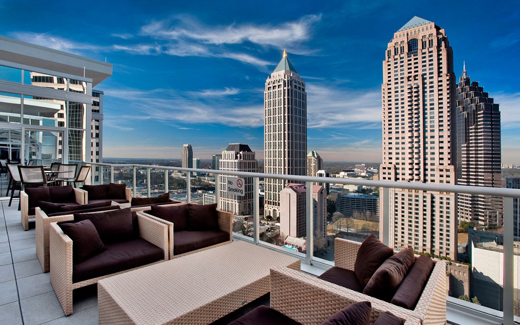 a view of the city skyline from a balcony with couches and tables
