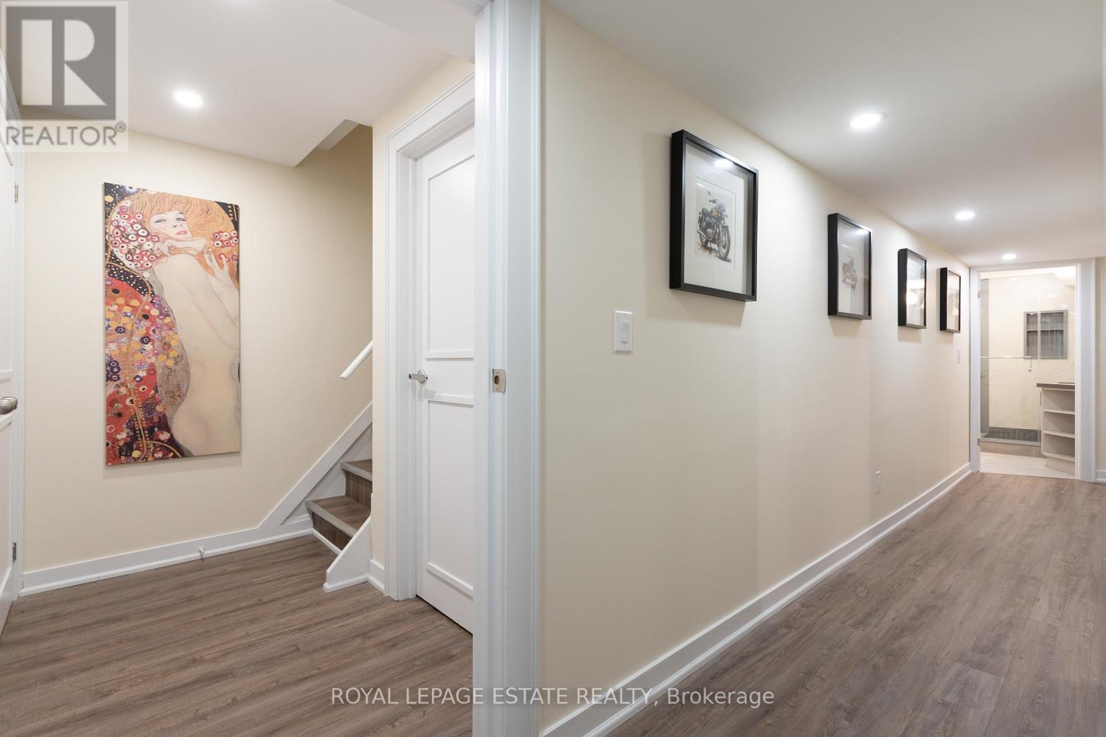 A hallway with a painting on the wall and a door on the right.