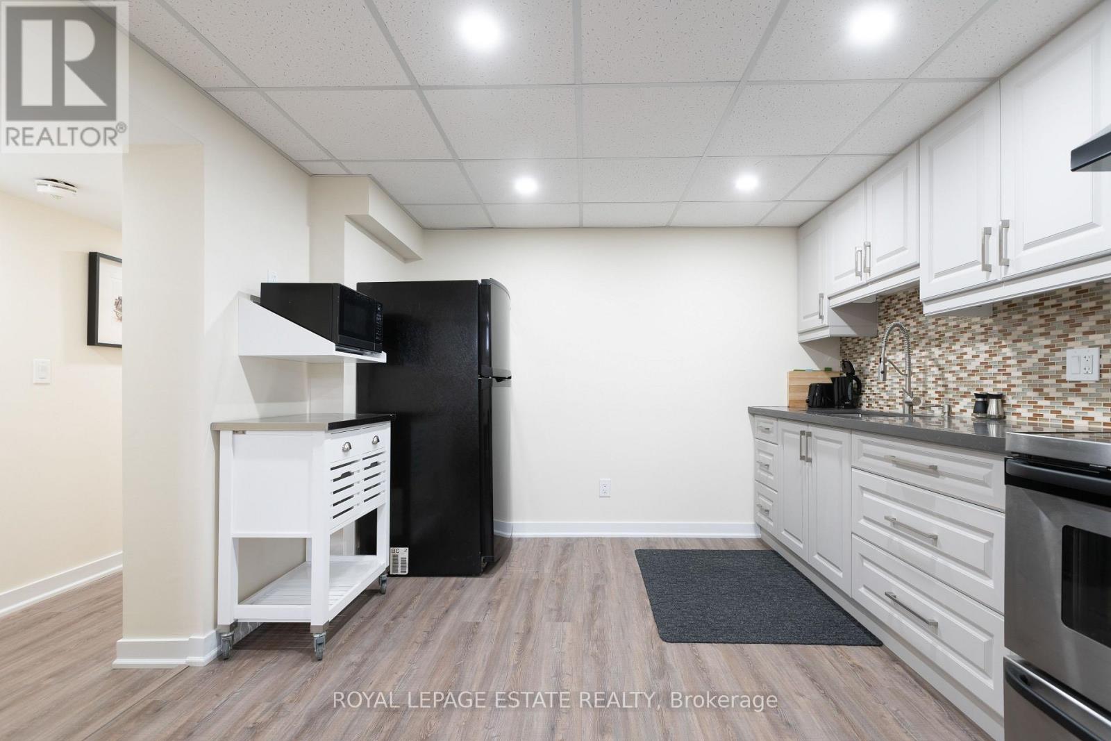 A kitchen with white cabinets and a black fridge.