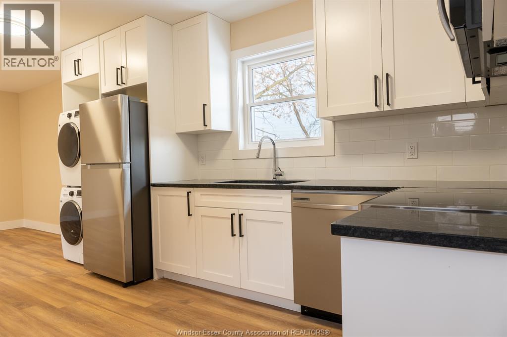 A kitchen with white cabinets and a black countertop.