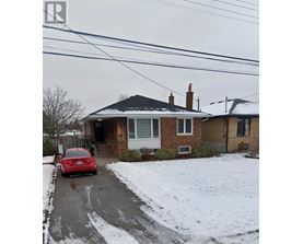 A red car is parked in front of a house with a snow-covered ground.