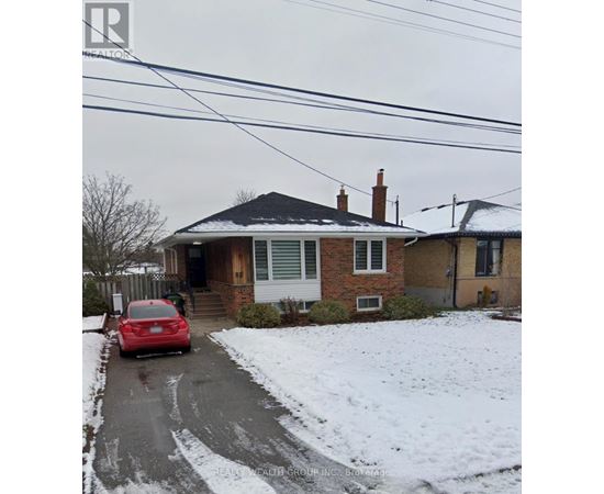 A red car is parked in front of a house with a snow-covered ground.