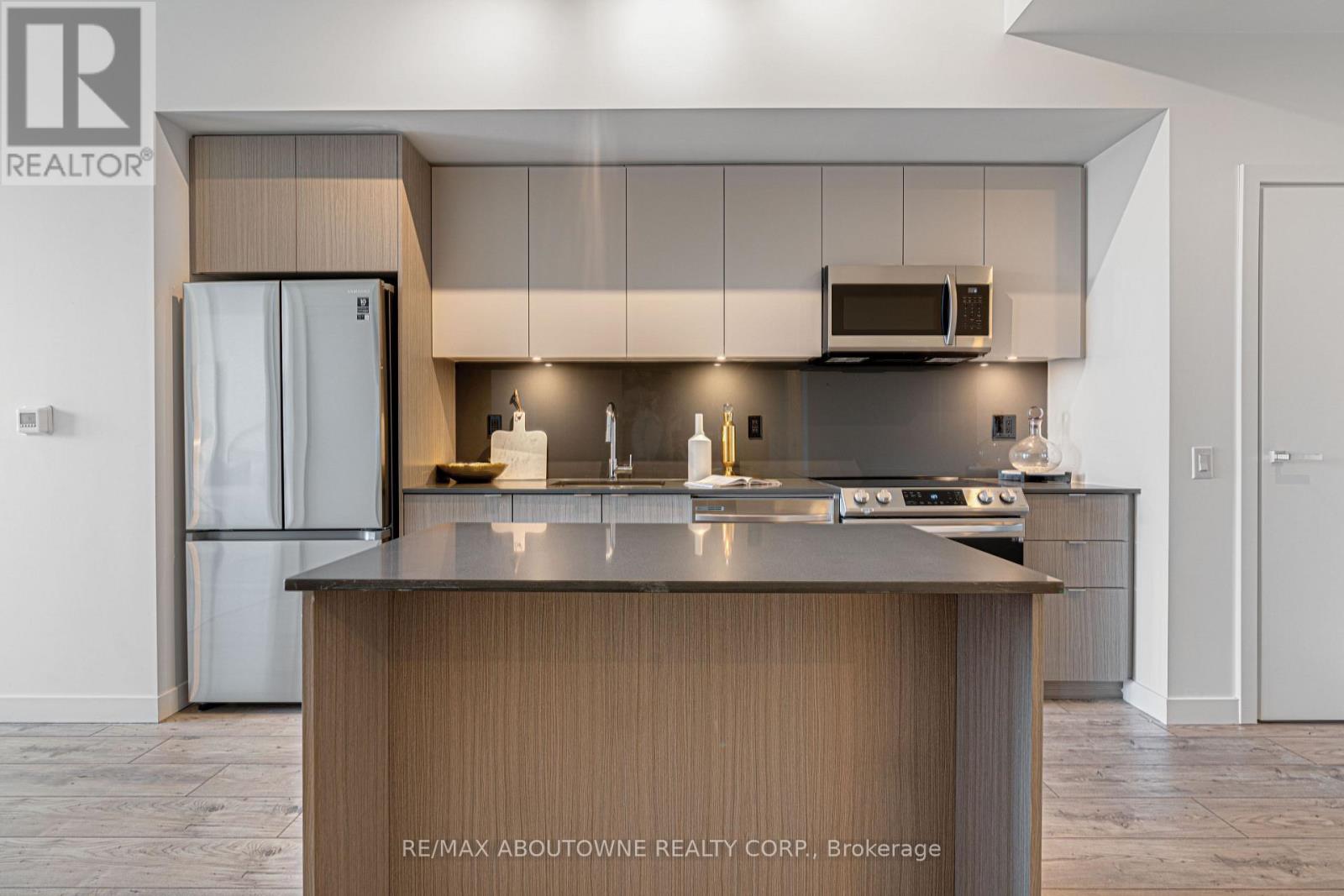 A modern kitchen with a refrigerator, stove, and microwave.