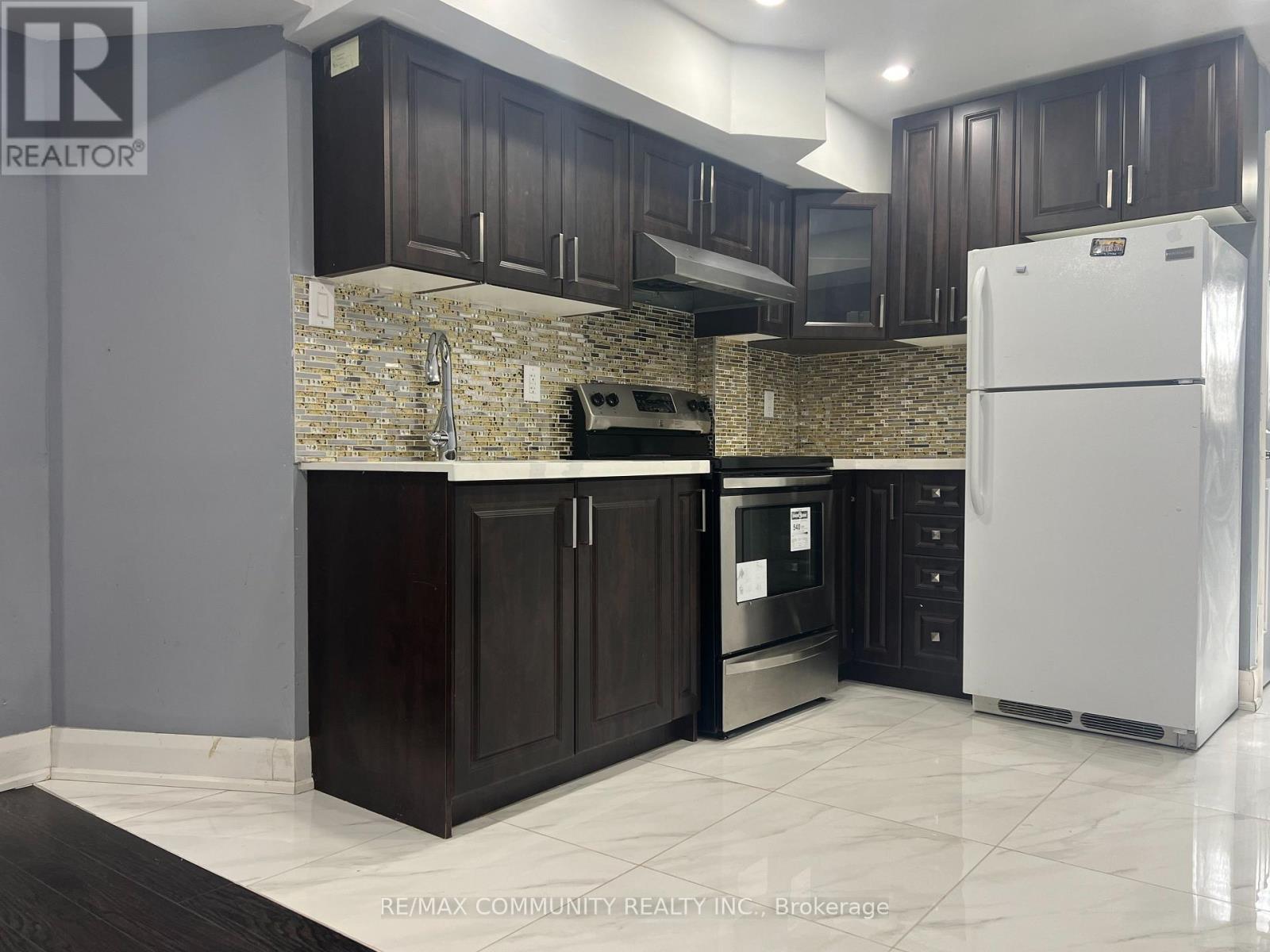 A kitchen with a white refrigerator and dark brown cabinets.