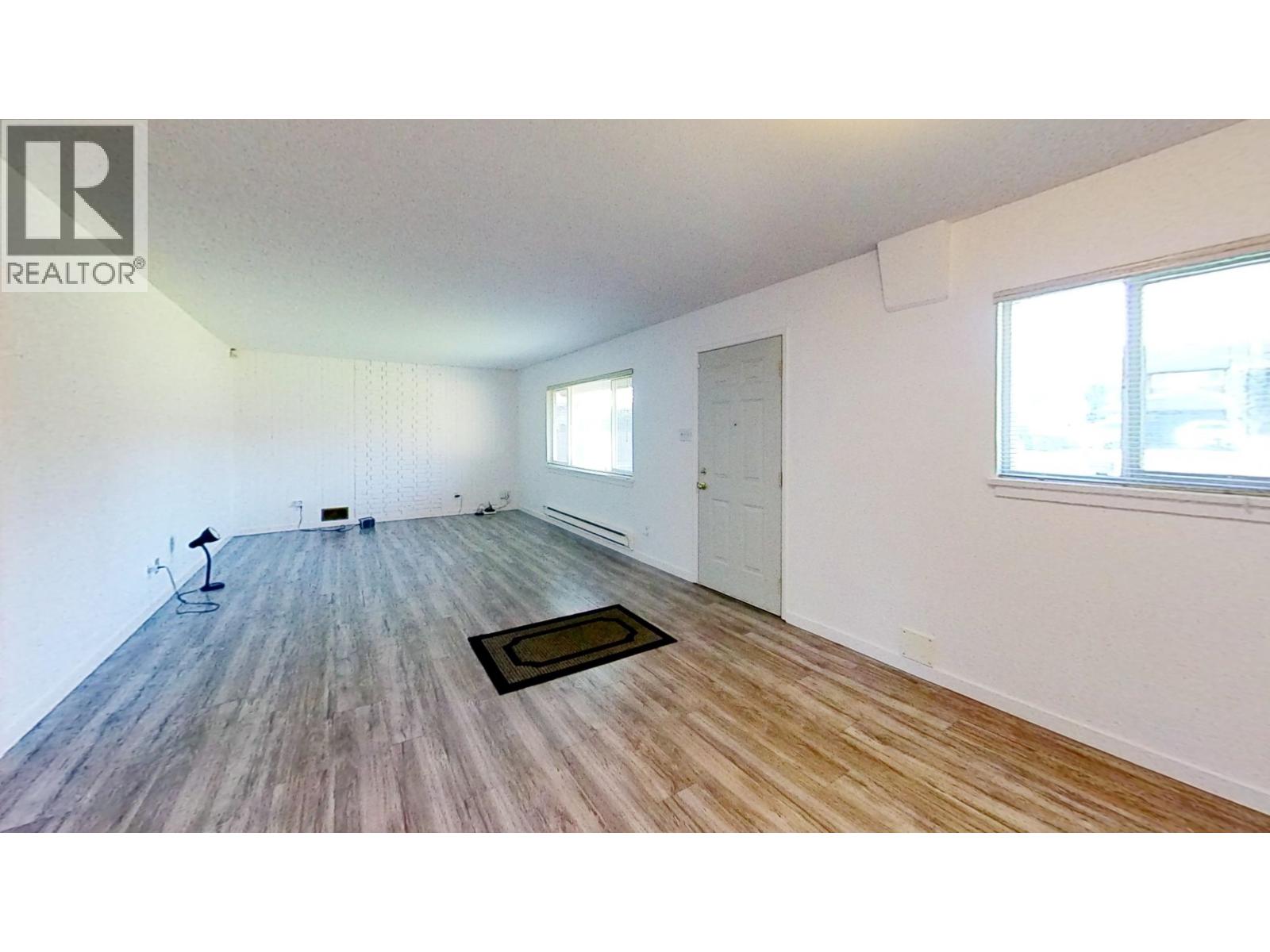 A room with wooden flooring and a window on the right side.