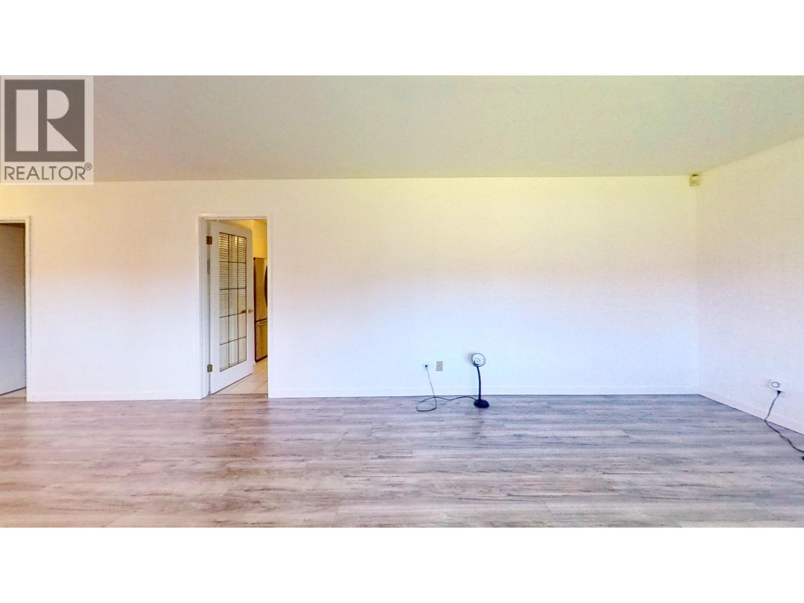A room with a wooden floor and a door on the left side.