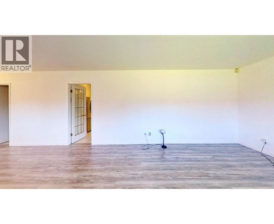 A room with a wooden floor and a door on the left side.