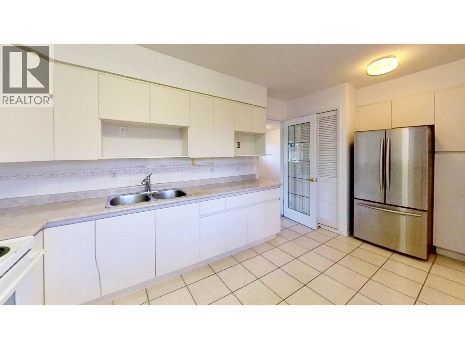 A kitchen with white cabinets and a stainless steel refrigerator.