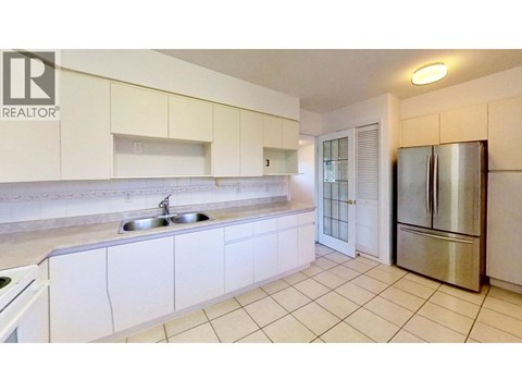 A kitchen with white cabinets and a stainless steel refrigerator.