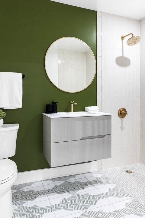 A white sink with a round mirror above it.