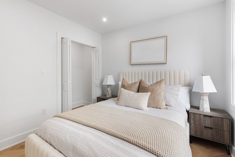 A bedroom with a large bed and two lamps.