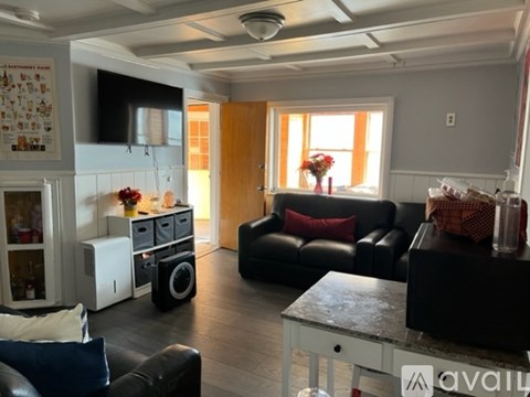 A living room with a black leather couch and a white microwave above it.