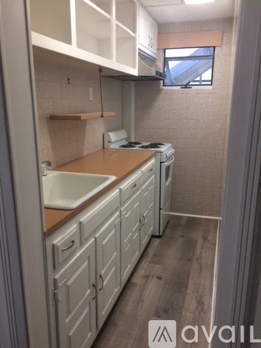 A small kitchen with white cabinets and a wooden counter.