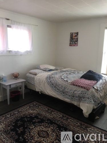 A bedroom with a bed, a small table, and a rug.