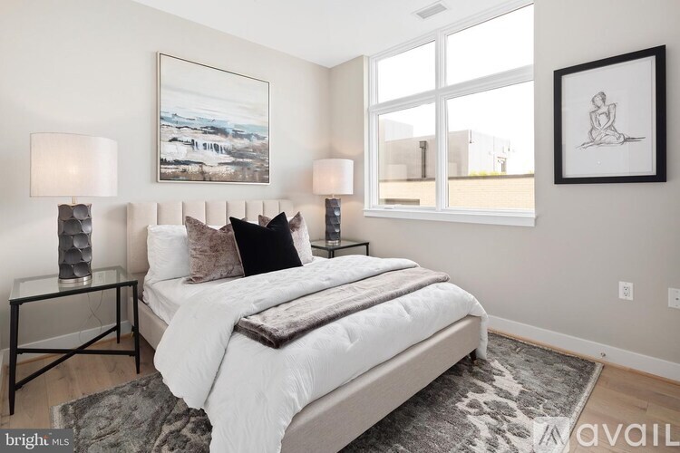 A bedroom with a large bed, two lamps, and a framed picture on the wall.