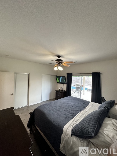 A bedroom with a bed, dresser, and sliding glass doors.