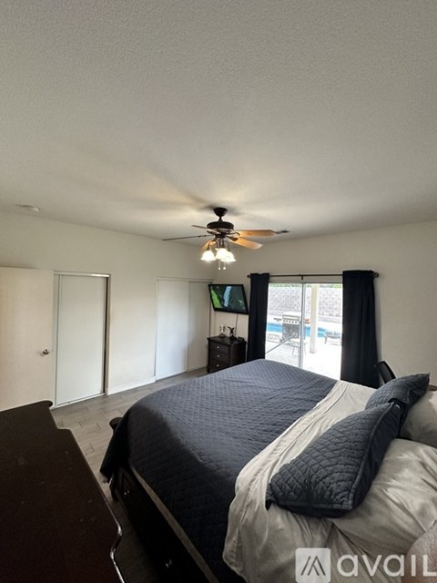 A bedroom with a bed, dresser, and sliding glass doors.