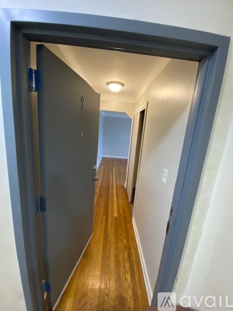 A hallway with a wooden floor and a metal door on the left.