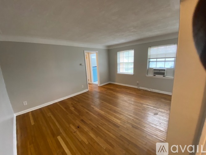 A room with wooden flooring and a door leading to another room.