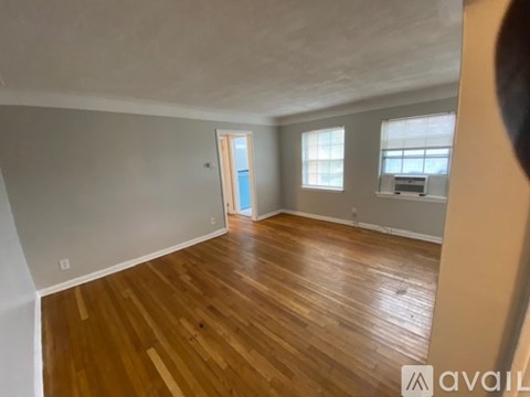 A room with wooden flooring and a door leading to another room.