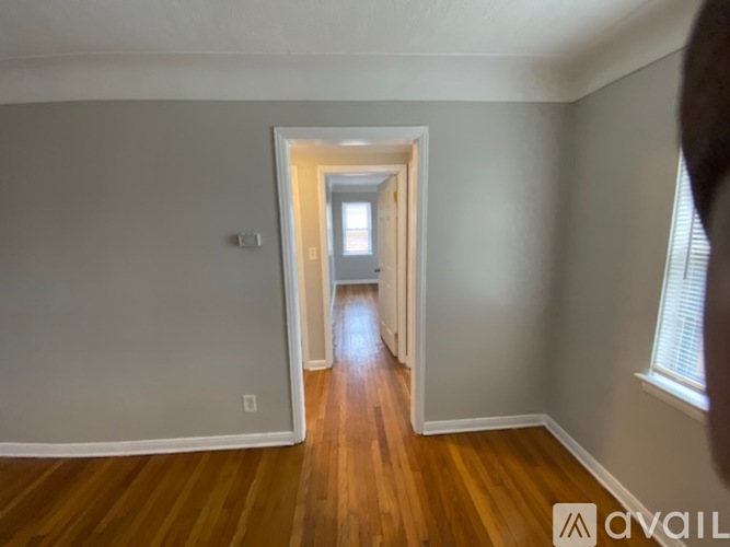 A hallway with wooden floors and white walls leading to a door.