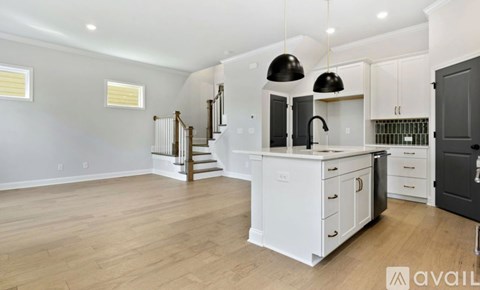 A spacious kitchen with white cabinets and a black fridge.