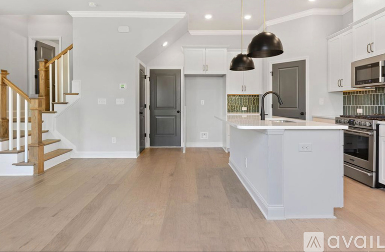 A spacious kitchen with a wooden floor and white walls.
