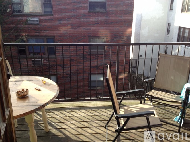 A balcony with a table and chairs overlooking a brick building.