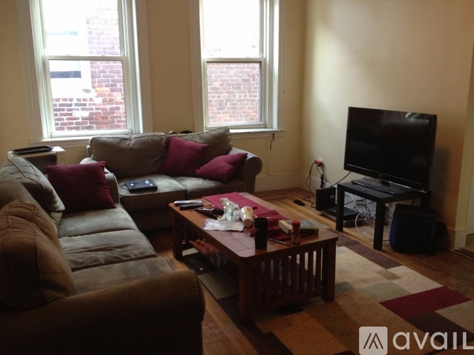 A living room with a brown couch, a coffee table, and a television.