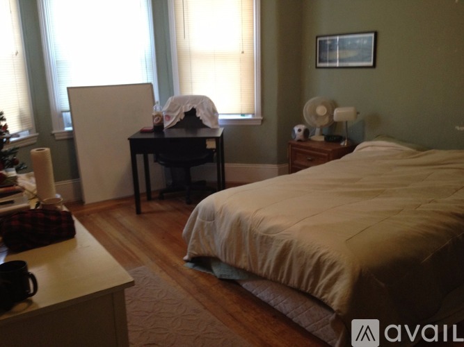 A bedroom with a bed, a desk, and a chair.