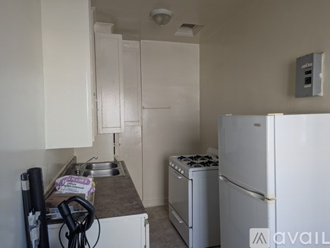 A kitchen with a white fridge, sink and cabinets.