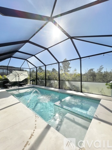 A pool inside a glass house with sunlight shining through.